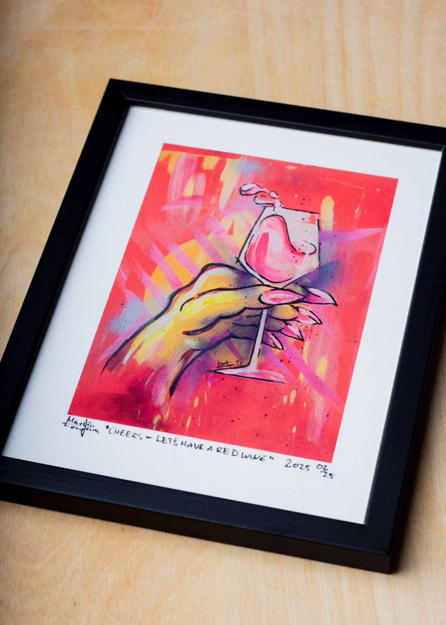 Zeitgenössischer gerahmter Kunstdruck eines figurativen Gemäldes mit stilisierter Hand und Weinglas in intensiven Neonfarben. Detailreiche Darstellung in Pink-, Gelb- und Orangetönen auf leuchtendem Hintergrund, präsentiert als signierter Print mit Passepartout in schwarzem Rahmen auf Holzoberfläche.