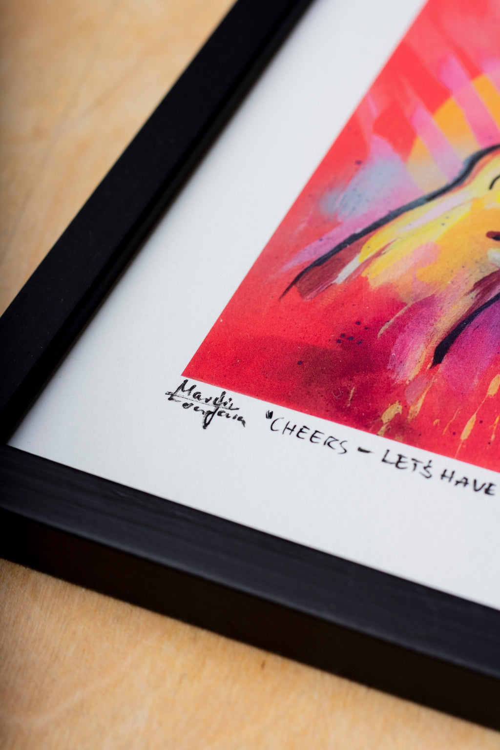 Zeitgenössischer gerahmter Kunstdruck eines figurativen Gemäldes mit stilisierter Hand und Weinglas in intensiven Neonfarben. Detailreiche Darstellung in Pink-, Gelb- und Orangetönen auf leuchtendem Hintergrund, präsentiert als signierter Print mit Passepartout in schwarzem Rahmen auf Holzoberfläche mit Fokus auf Signe.