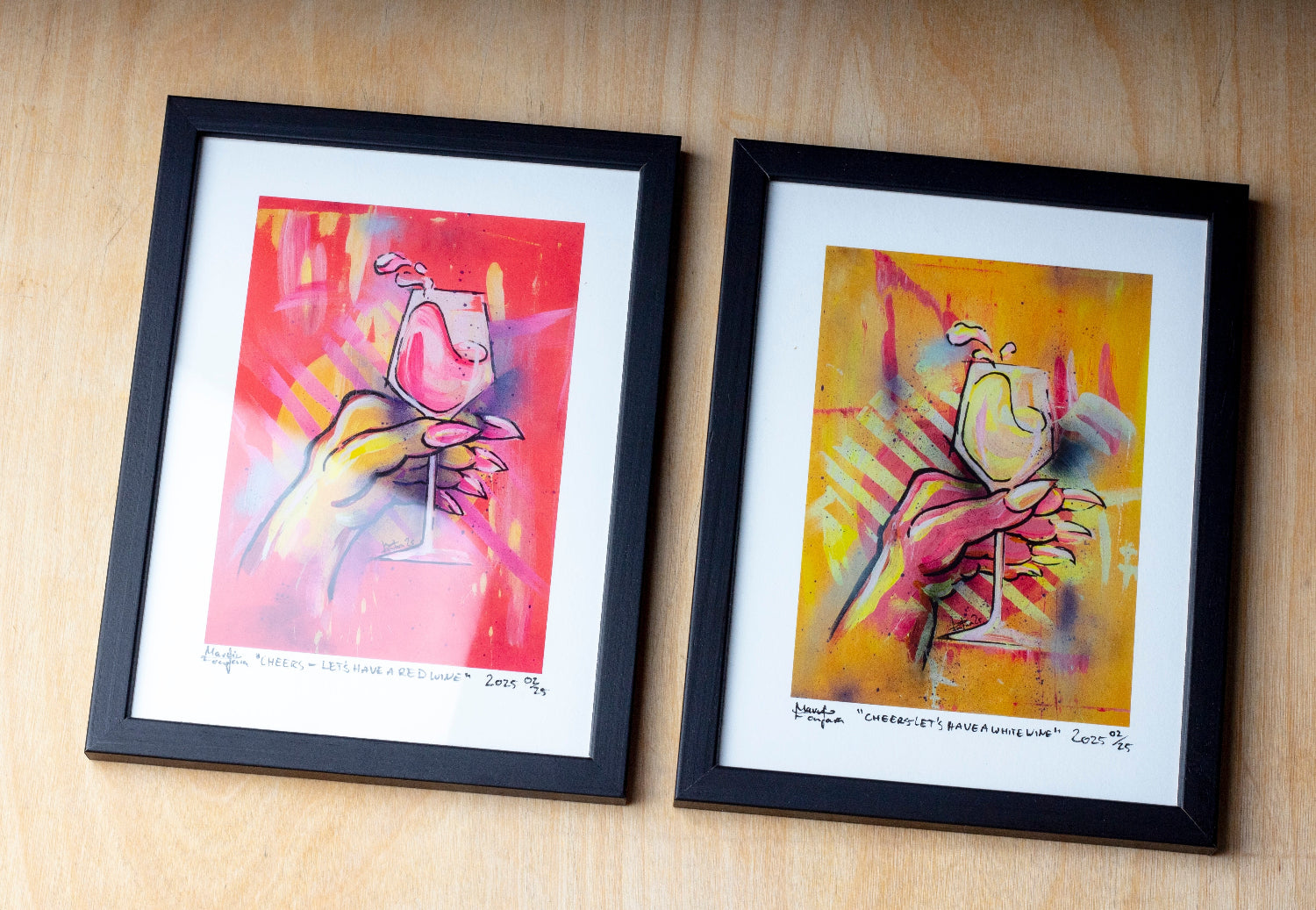 Zeitgenössischer gerahmter Kunstdruck zweier figurativer Gemälde mit stilisierten Händen und Weingläsern in intensiven Neonfarben. Detailreiche Darstellung in Pink-, Gelb- und Orangetönen auf leuchtendem Hintergrund, präsentiert als signierter Print mit Passepartout in schwarzem Rahmen auf Holzoberfläche.