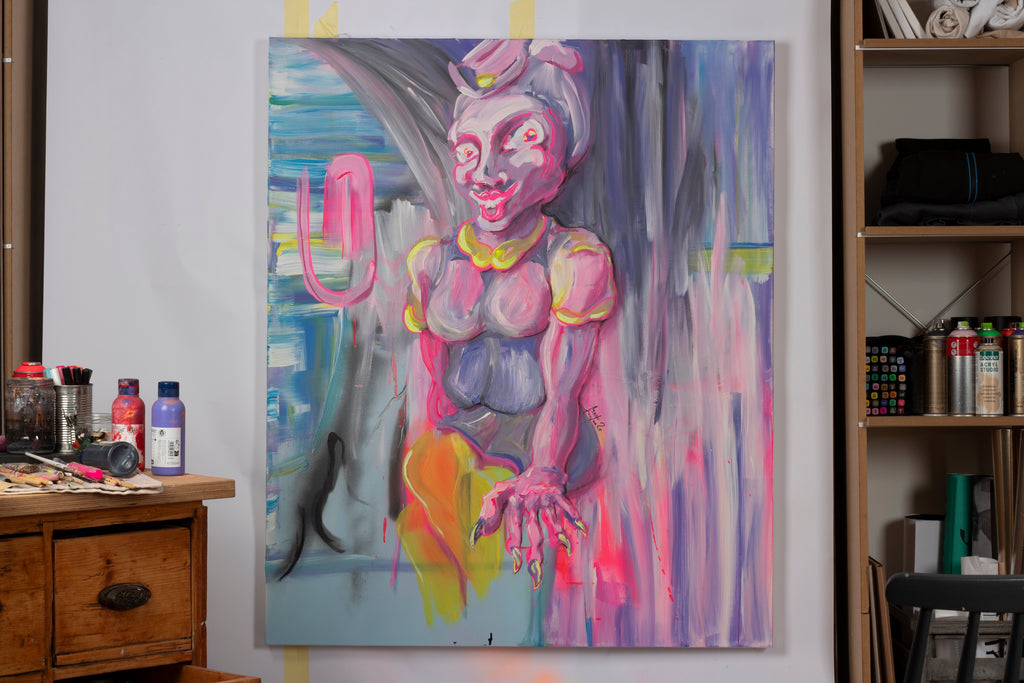 Zeitgenössisches figuratives Gemälde einer stilisierten weiblichen Figur mit überzeichneten Gesichtszügen und Neonakzenten – expressive Malerei zu Identität, Inszenierung. Sitzende Figur in Rosa-, Grau- und Gelbtönen mit betonten Augen und Händen vor abstrakt verlaufendem Hintergrund mit gestischen Pinselspuren in Blau, Grau und Pink im Atelier mit Spraydosen, Farbtuben, Pinseln und Markern präsentiert.